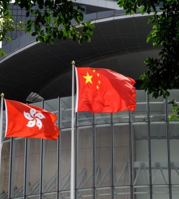 Flags of China (C) and Hong Kong (L) flutter in the wind outside the Legislative Council complex in Hong Kong on March 30, 2021. (Photo by Anthony WALLACE / AFP)