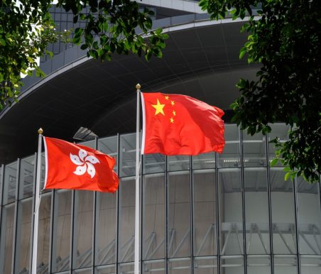 Flags of China (C) and Hong Kong (L) flutter in the wind outside the Legislative Council complex in Hong Kong on March 30, 2021. (Photo by Anthony WALLACE / AFP)